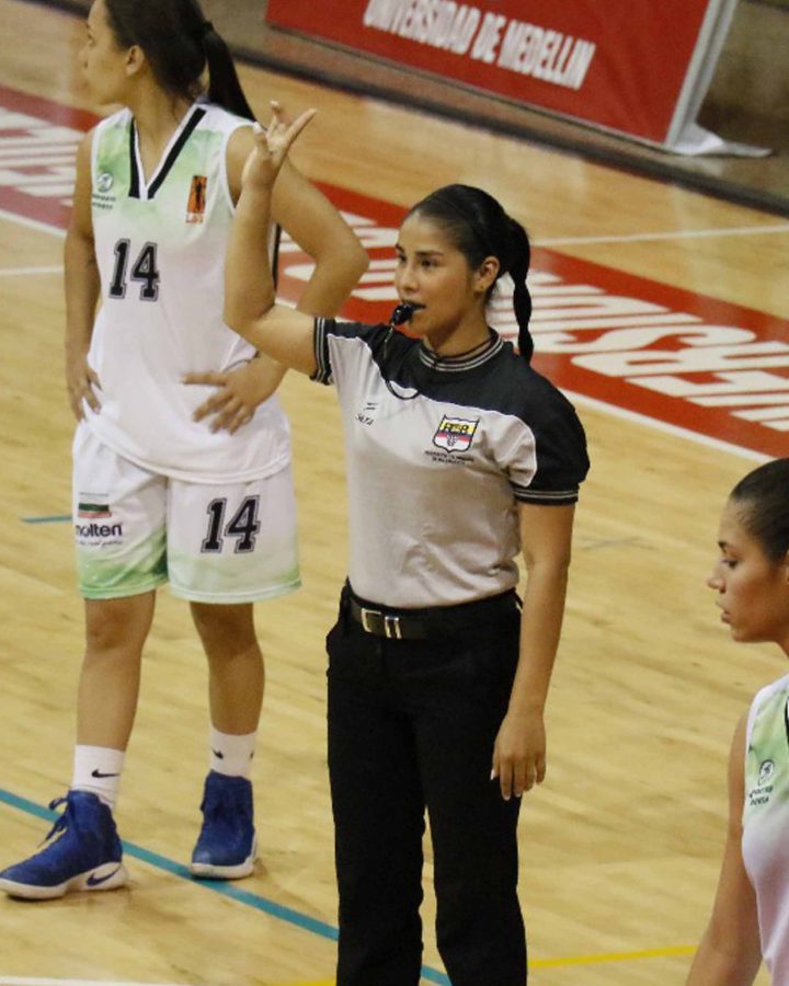 Árbitra de la Asociación CABA señalando una falta durante un partido de baloncesto en Medellín.
